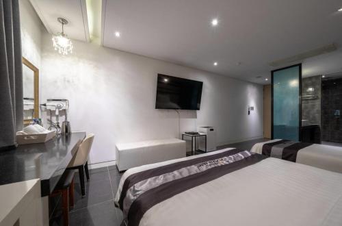 a bedroom with two beds and a tv on the wall at Hotel Cube in Incheon