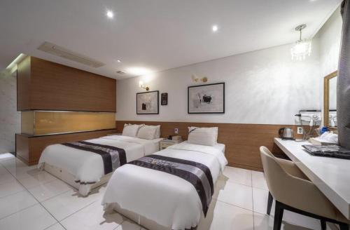 a hotel room with three beds and a desk at Hotel Cube in Incheon