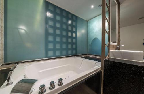 a bathroom with a tub and a sink at Hotel Cube in Incheon