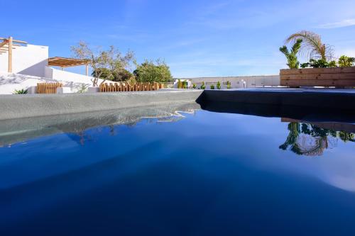 a swimming pool with blue water in front of a house at Athiri Luxury Suites in Perivolos