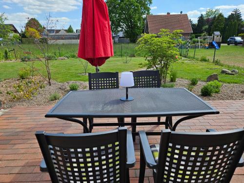 einem schwarzen Tisch mit Stühlen und einem roten Regenschirm in der Unterkunft Stilvoll eingerichtetes Ferienhaus in ruhiger Lage in Bremerhaven