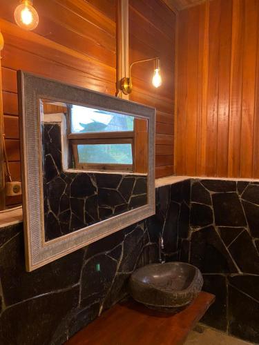 a bathroom with a mirror and a stone toilet at Rimba eco Resort in Tomohon