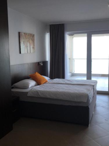 a bedroom with a bed with an orange pillow and a window at Hotel Vienna in Herceg-Novi
