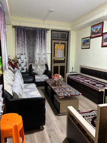 a living room with couches and tables at BLUE DUKE HOMESTAY in Ravangla