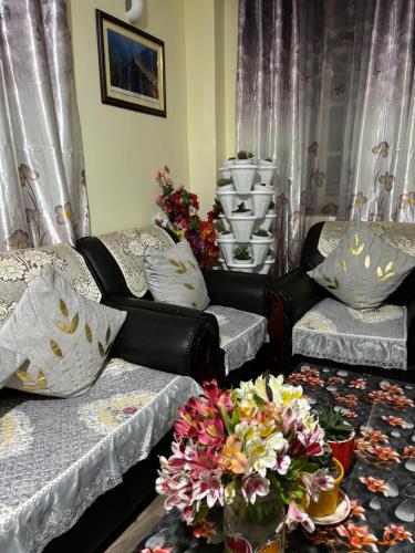 a living room with two couches and a vase of flowers at BLUE DUKE HOMESTAY in Ravangla