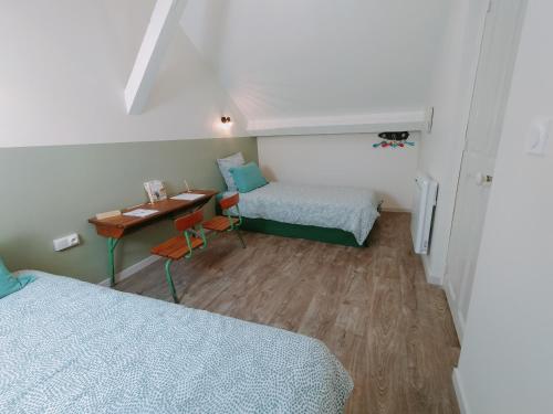 a small room with two beds and a table at L'école buissonnière in Laroque-dʼOlmes