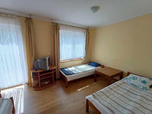 a room with two beds and a tv in it at Pokoje Augustowskie in Augustów