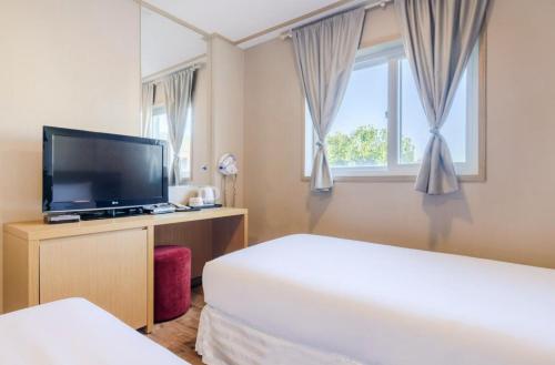 Cette chambre comprend 2 lits et une télévision à écran plat. dans l'établissement Pine Hill Hotel, à Seogwipo