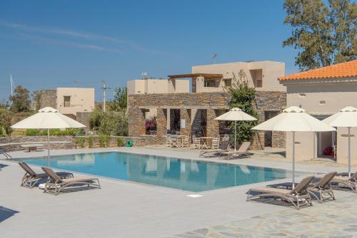 a swimming pool with chairs and umbrellas at Vourkari Village in Vourkarion