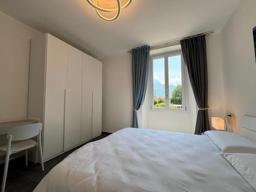 a bedroom with a bed and a desk and a window at Appartamento Rigoletto, garden, air comnditioning - Larihome A69 in Dongo