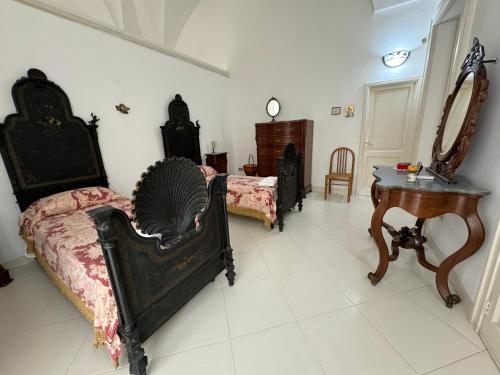 a room with four beds and a table and a mirror at Palazzo Quey in Lecce