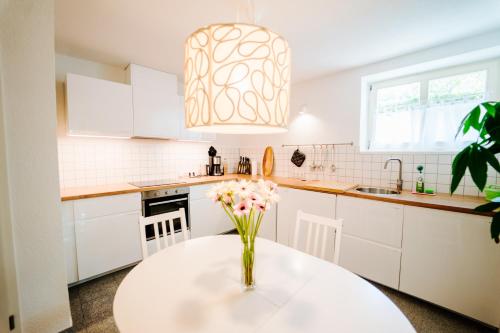 a white kitchen with a vase of flowers on a table at Villa Levin - 56qm, bis 4 Personen, free Wifi & parken in Steudnitz