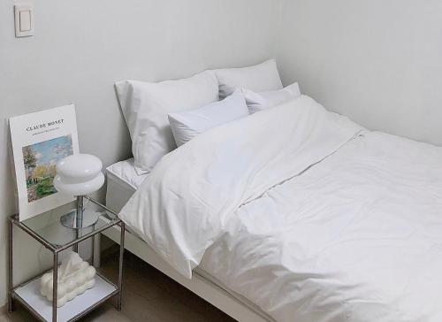 a white bed with white sheets and pillows at Torry House in Busan