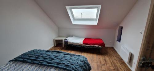 a attic room with two beds and a window at Maison à la campagne. in Audembert