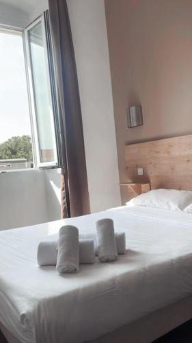 a white bed with two towels on it with a window at Hotel Riviera in Bastia
