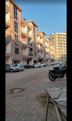 stay inn hotel Chandigarh في Mohāna: موقف للسيارات مع وقوف السيارات أمام المباني