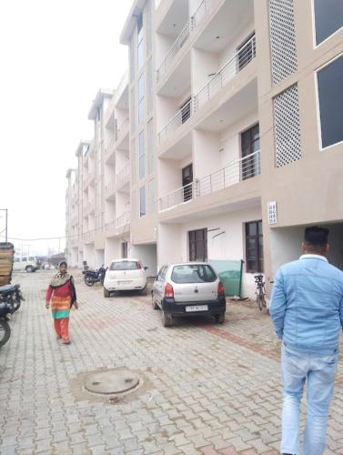 stay inn hotel Chandigarh في Mohāna: رجل وامرأة يسيران أمام مبنى