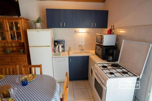 Il comprend une cuisine équipée d'un réfrigérateur blanc et d'une cuisinière. four supérieur dans l'établissement Maison climatisée à 600m de la plage, à Vias