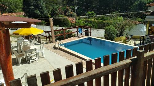 - Piscina con mesa y sombrilla en Hostel Yellow House MG, en Itamonte