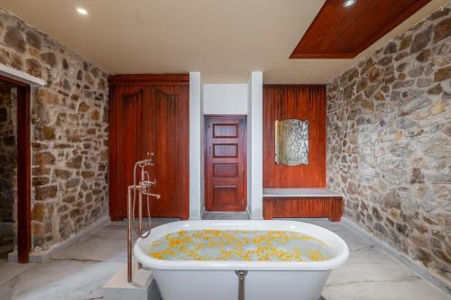 a bath tub in a room with a stone wall at Juna Mahal Jungle Resort Ranthambore in Sawāi Mādhopur