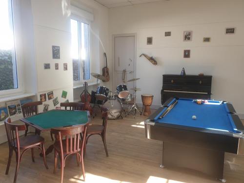 a room with a pool table and a piano at L'école buissonnière in Laroque-dʼOlmes
