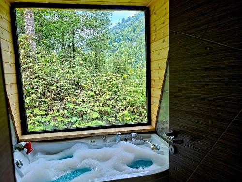 a bathroom with a large window with a bath tub at Zayna bungalov in Çamlıhemşin