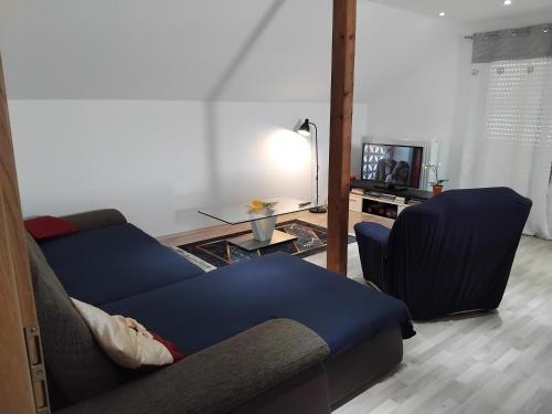 sala de estar con sofá azul y TV en Ferienwohnung Teranga, en Jettingen-Scheppach