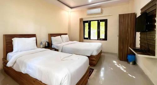 1 dormitorio con 2 camas y TV de pantalla plana en Samarth Resort, en Bhurkīā