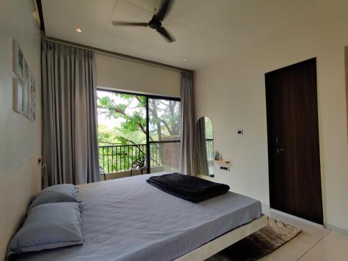 a bedroom with a bed and a large window at The Marigold Villa in Pune