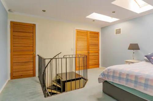 Schlafzimmer mit einem Bett und Holztüren in der Unterkunft Luxurious 3 bedroom beachfront - panoramic views in Port Adelaide