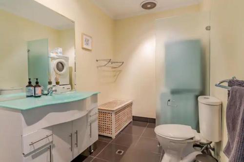 y baño con aseo, lavabo y espejo. en Luxurious 3 bedroom beachfront - panoramic views, en Port Adelaide