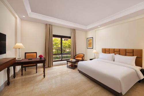 um quarto com uma grande cama branca e uma secretária em V Sarovar Portico MI Road Jaipur em Jaipur