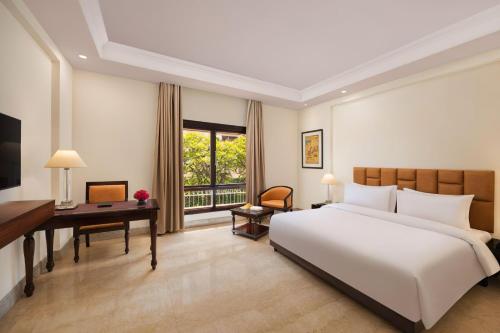 ein Schlafzimmer mit einem großen weißen Bett und einem Schreibtisch in der Unterkunft V Sarovar Portico MI Road Jaipur in Jaipur