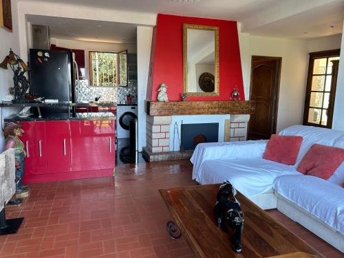 Elle comprend un salon doté d'un mur rouge et d'une cheminée. dans l'établissement Cassis appartement vue mer balneo, à Cassis