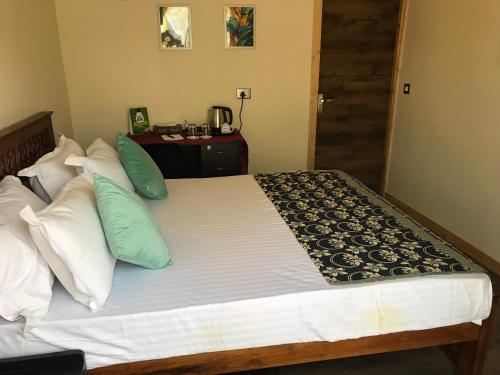 a bedroom with a large bed with green and white pillows at Chan Beach Resort & Hotel in Bahūr