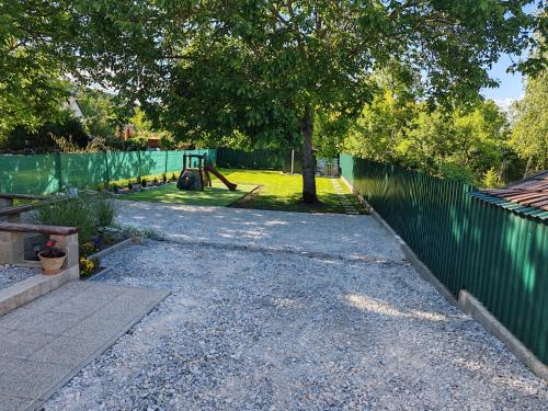 a gravel driveway with a fence and a playground at Mamácska Apartmanok in Bogács