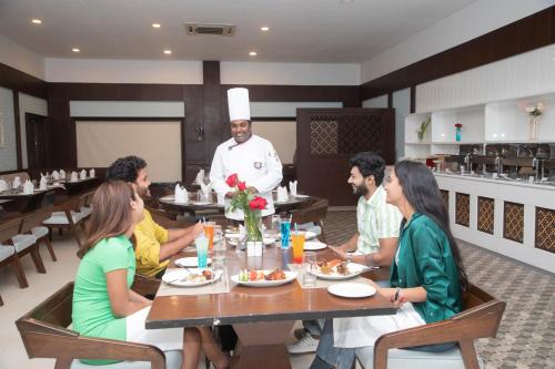 a group of people sitting around a table in a restaurant at The Greenfields Resort and Convention in Venkatāpur