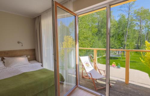 a bedroom with a bed and a sliding glass door at Domki Apartamentowe Bravo in Bobolin