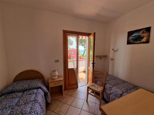 1 Schlafzimmer mit 2 Betten und einer Tür zu einer Terrasse in der Unterkunft Appartamenti Fetovaia Elicriso in Fetovaia