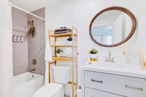 ein Badezimmer mit einer weißen Toilette und einem Spiegel in der Unterkunft #BohoSleek King Bed Spa Shower-Near TopGolf Downtown Uptown BJCC Hoover Complex in Birmingham