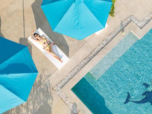 an overhead view of two people in a pool with blue umbrellas at 宛如梦境 一线海景6卧室别墅 超大私人泳池 免费早餐接机 私人影院健身房 in Phuket