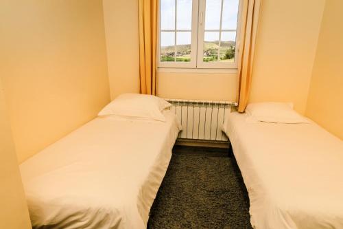 two beds in a small room with a window at Le Palais des Cerisiers in Azrou