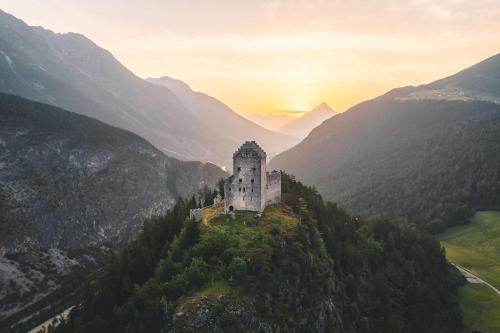a castle on top of a hill with mountains at Lechtaler Alpenblick Landeck - Privatzimmer & Ferienwohnung in Landeck