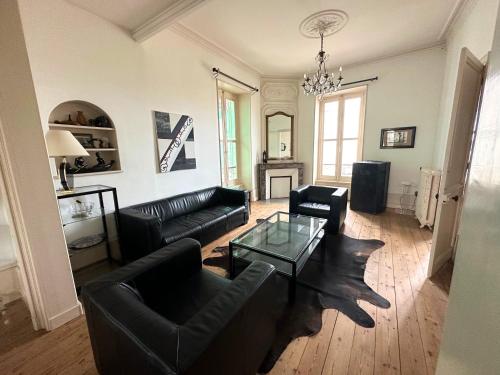 Elle comprend un salon doté d'un mobilier en cuir noir et d'un lustre. dans l'établissement Villa RENNAISSANCE - Proche Mer - Parking - Ménage & Linge inclus, à La Rochelle