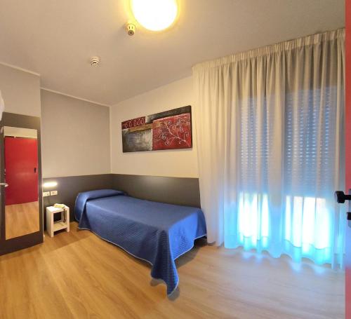 a bedroom with a blue bed and a window at Hotel Panorama in Lido di Jesolo