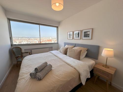 une chambre avec un grand lit avec une grande fenêtre dans l'établissement Le Panoramic, à Villeurbanne