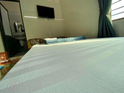 1 dormitorio con 1 cama blanca y TV en la pared en Nhà Nghỉ Thiên Tân 2 en Quang Ngai