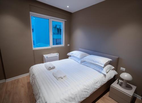 una camera da letto con un letto grande con lenzuola e cuscini bianchi di Dyrrhachium Elegance - Stylish Apartment City Center a Durrës