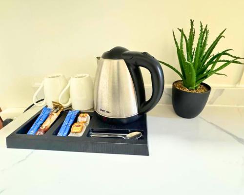 a coffee maker on a tray on a counter with a plant at البندقية للخدمات الفندقية BQ HOTEL SUITES in Buraydah