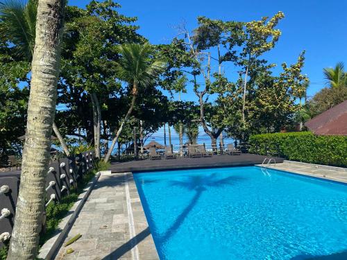 a swimming pool in a resort with trees at Juquehy - Condomínio de Frente para o Mar - Piscina Aquecida - Quadra de Tenis in Juquei